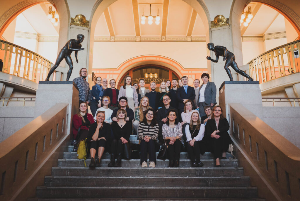 The project partners seat on the stairs of the National Museum in Szczecin, surrounded by the marble figures.