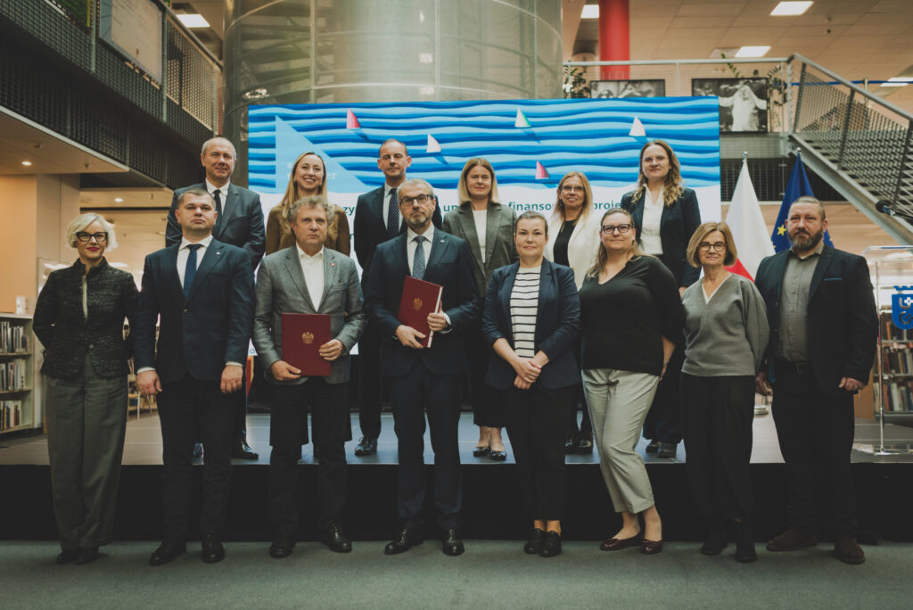 A group of people poses for the photo in front of the large banner with the Interreg South Baltic branding.